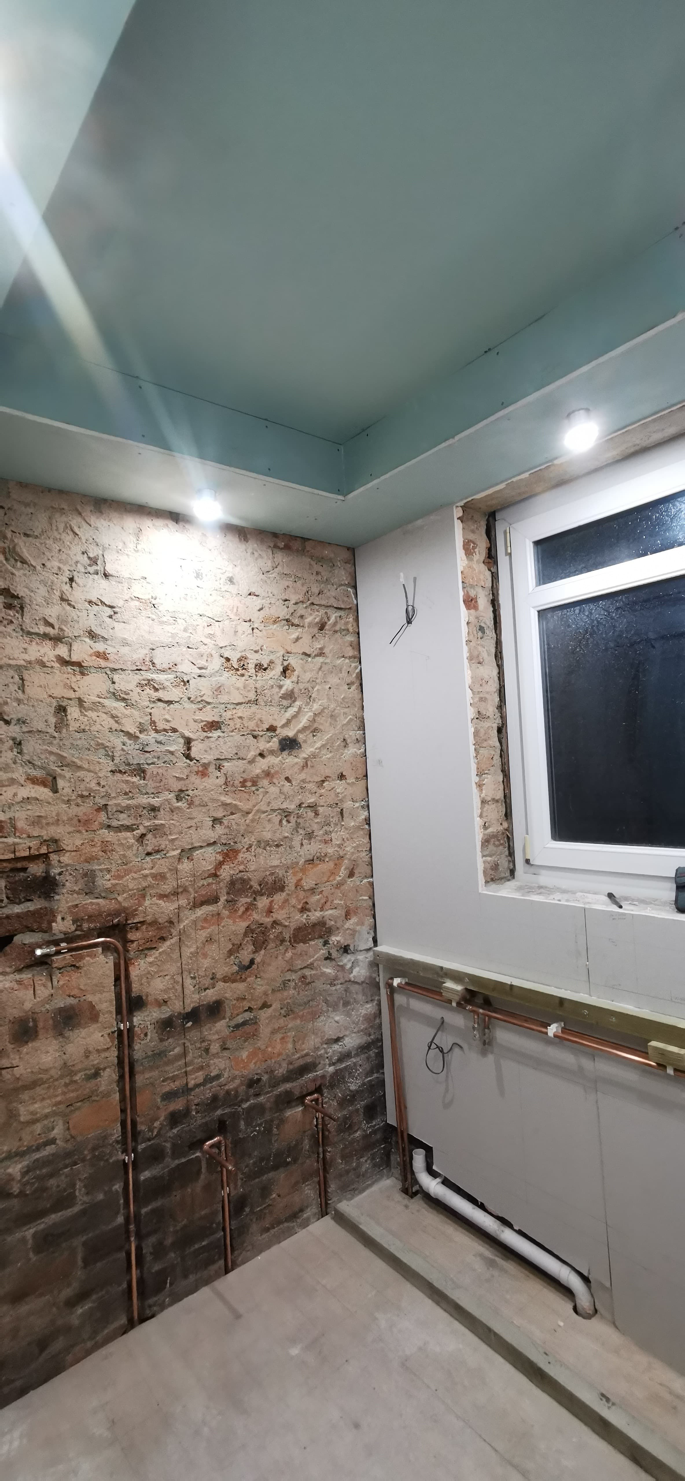 First-fix copper pipework against exposed brick ahead of a bathroom refit