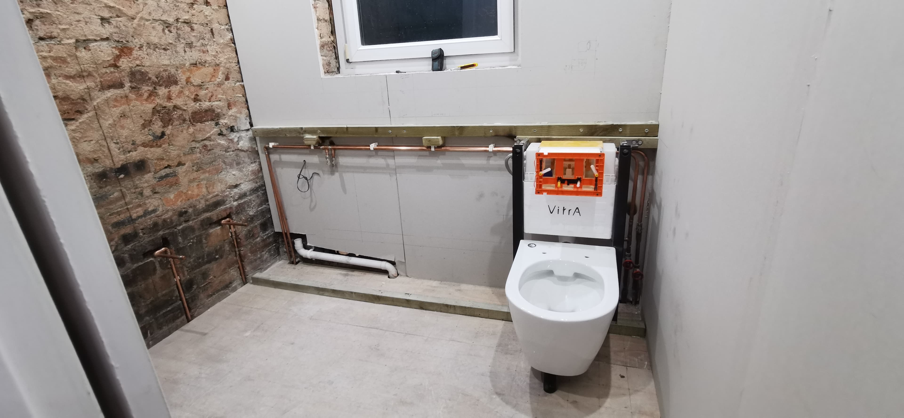 Bathroom first-fix plumbing with wall-hung WC frame and copper pipework